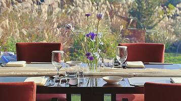 A dining table set with red chairs, a vase with flowers, and various glassware.