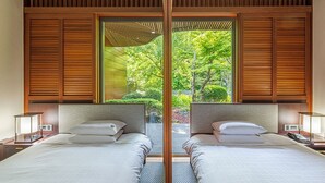 A modern hotel room with two beds, wooden paneling, and a large window offering a view of greenery. - Podo Hotel (Seogwipo)