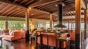 A spacious indoor area with wooden flooring, orange seating, and a large chimney. - Podo Hotel (Seogwipo)