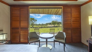 A hotel room with a large window, a bed, two armchairs, a small round table, and a lamp. - Podo Hotel (Seogwipo)