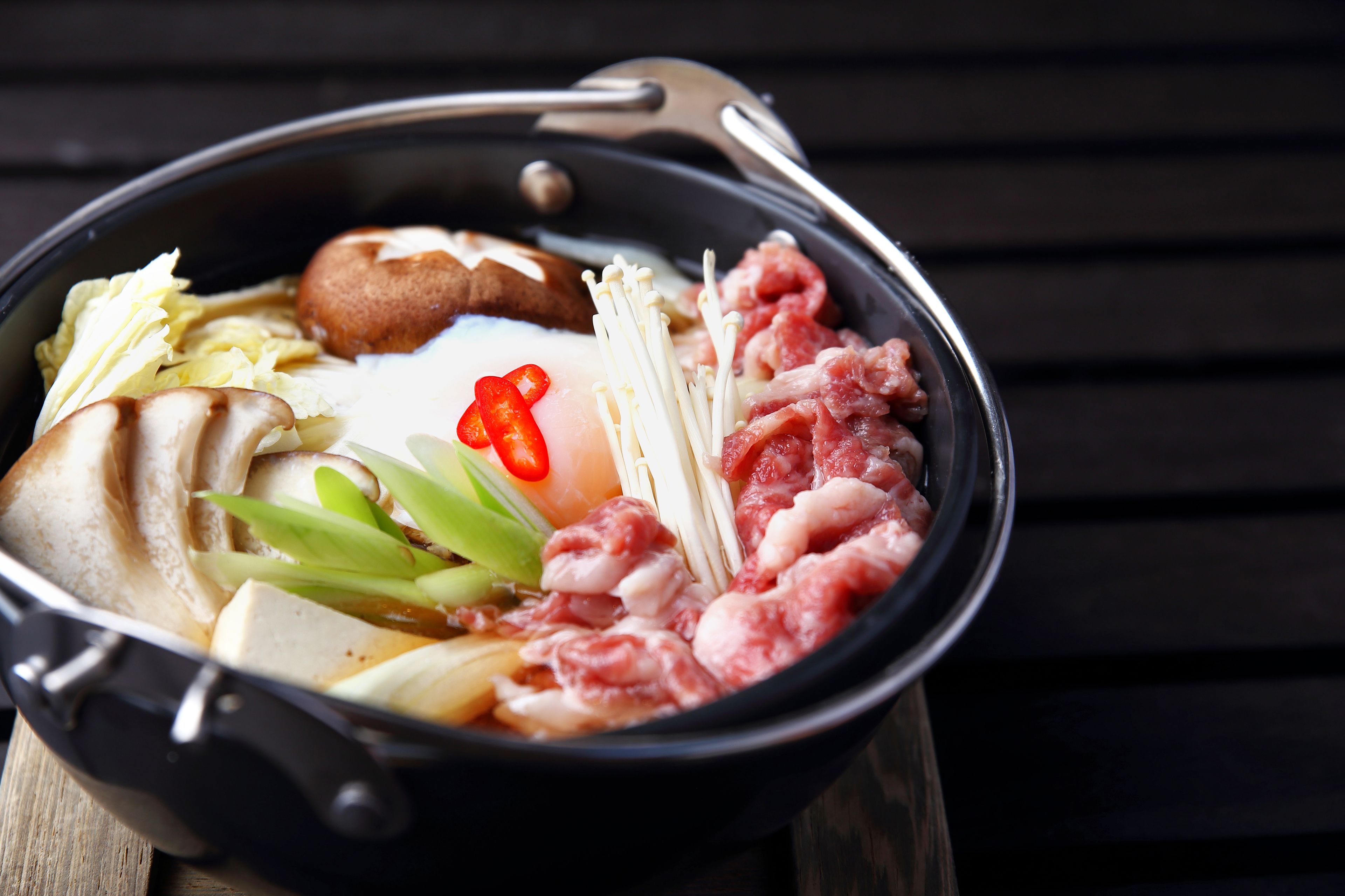 Um pote quente com diversos ingredientes como cogumelos, carne e legumes.
