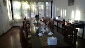 Un comedor con una mesa larga dispuesta para una comida, rodeado de sillas, con una ventana que proporciona luz natural.
