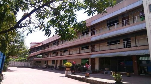 A multi-story building with balconies, potted plants, and a paved courtyard.