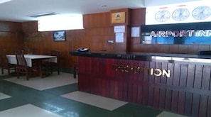 A reception desk with a clock and a sign that reads "AIRPORT INN". - Airport Inn (Yangon)