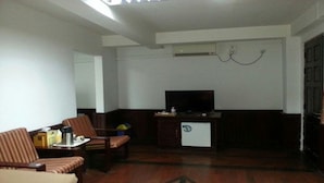 Una sala de estar con un sofá, dos sillones, un televisor y una mesita.