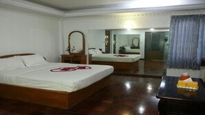 Habitación de hotel con dos camas, muebles de madera, un espejo y una mesita con fruteros.