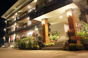 A multi-story hotel with balconies, a brick facade, and potted plants. - Nan Treasure (Phu Phiang)