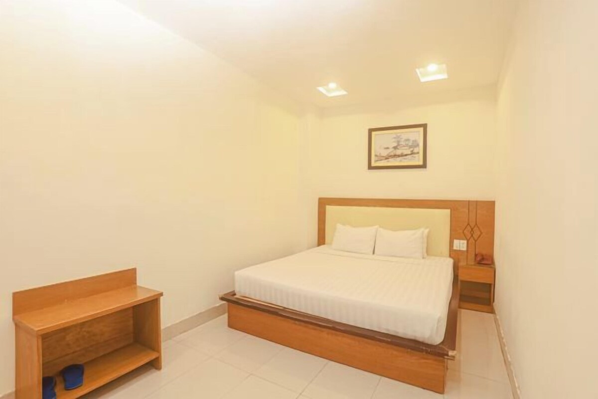 A bedroom with a wooden bed frame, a small wooden bench, and a nightstand.