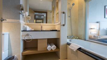 A modern bathroom with a bathtub, a sink with a mirror, a towel rack, and a trash bin.
