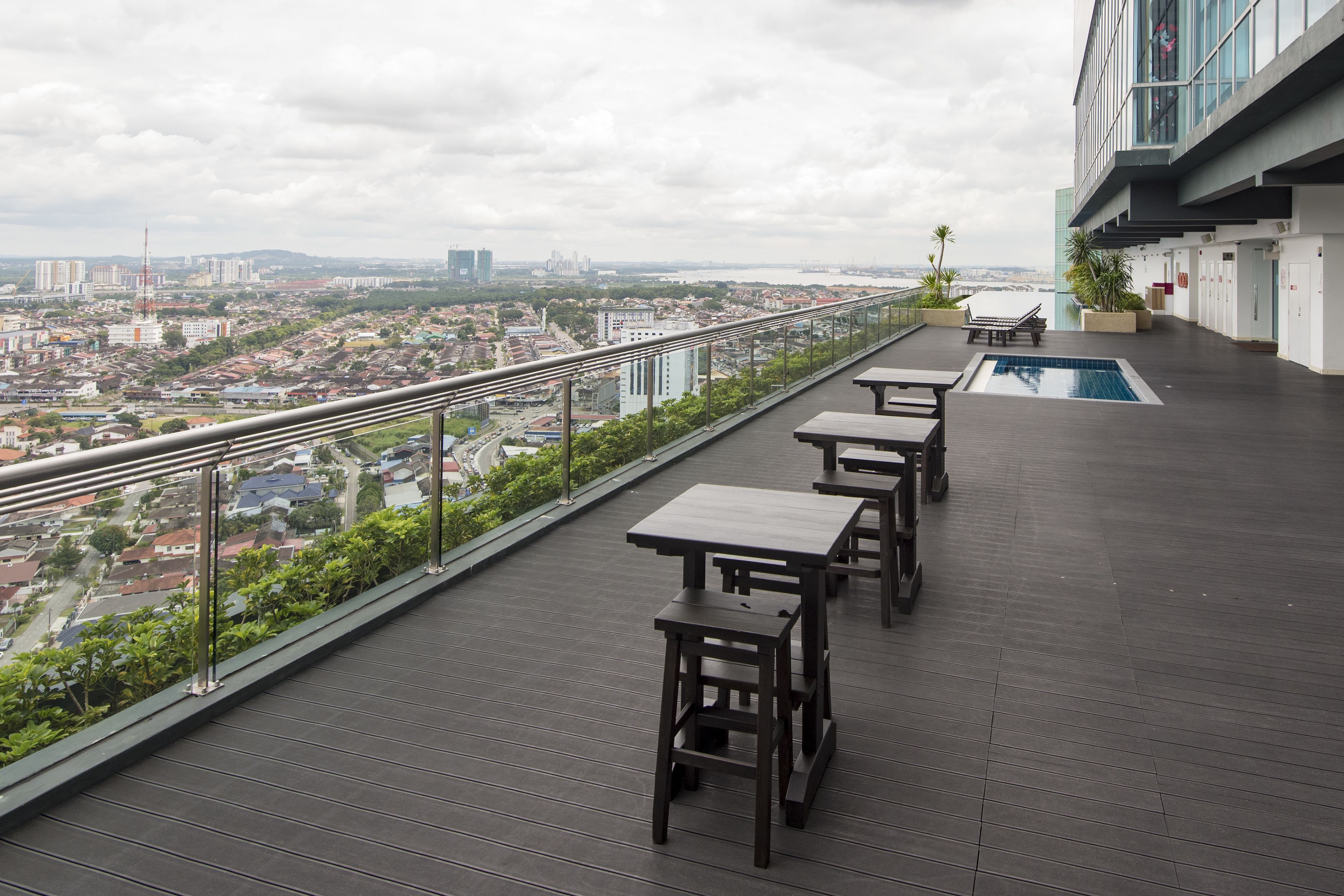 A rooftop terrace with a pool, dining tables, and a view of the cityscape.