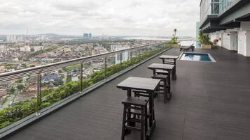 A rooftop terrace with a pool, dining tables, and a view of the cityscape.