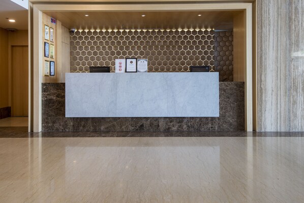 Una recepción con mostrador de mármol, pared con diseño hexagonal y certificados enmarcados.