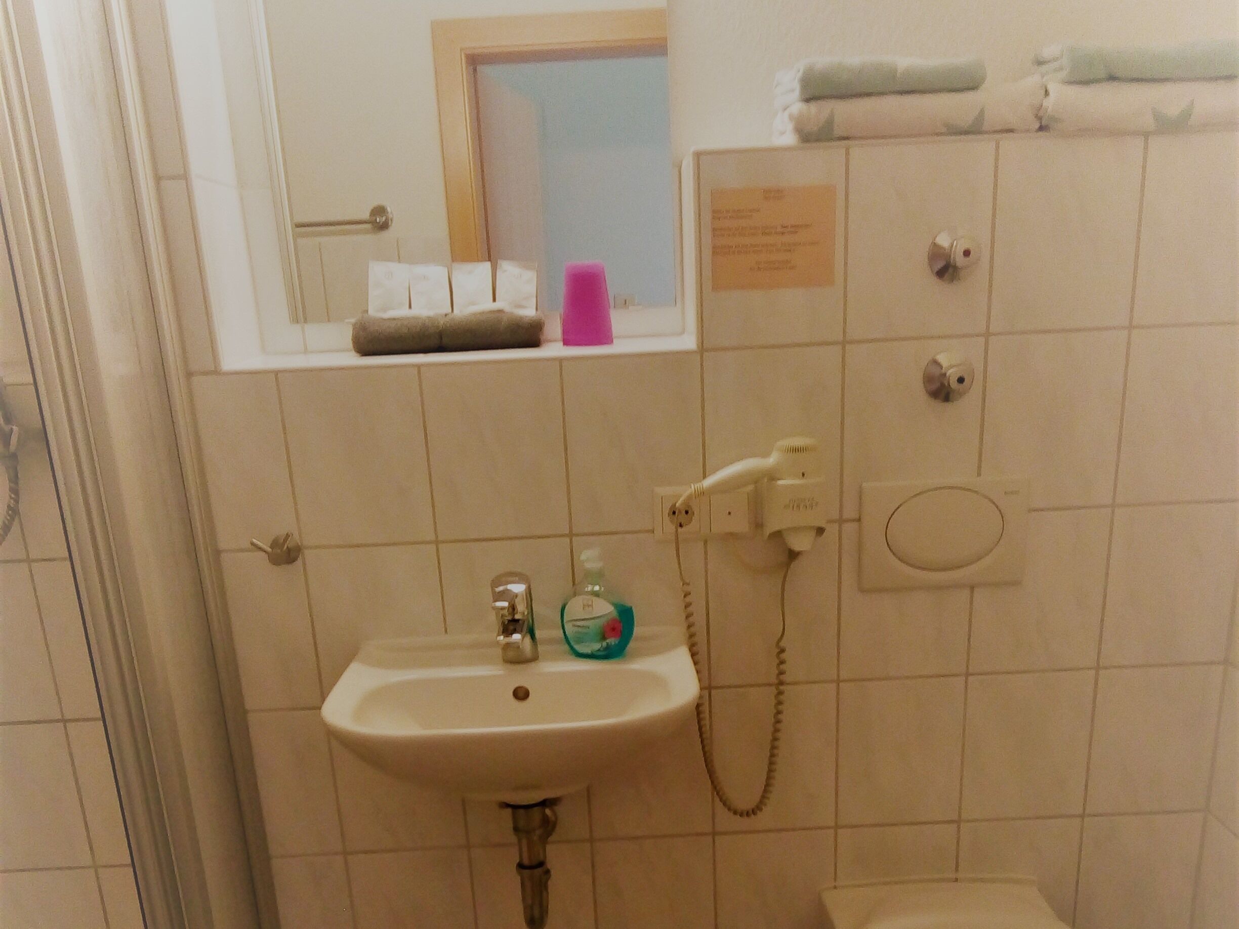 Une salle de bain équipée d’un lavabo, d’un miroir, d’un porte-serviettes et d’une douche.