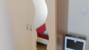 A bedroom with a bed, a wardrobe, and a heater. - Hotel Kalimera (Heddesheim)
