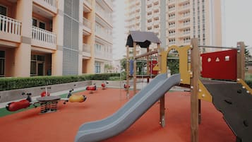 Children can play on the slide, swings, and climbing structure in this outdoor play area.