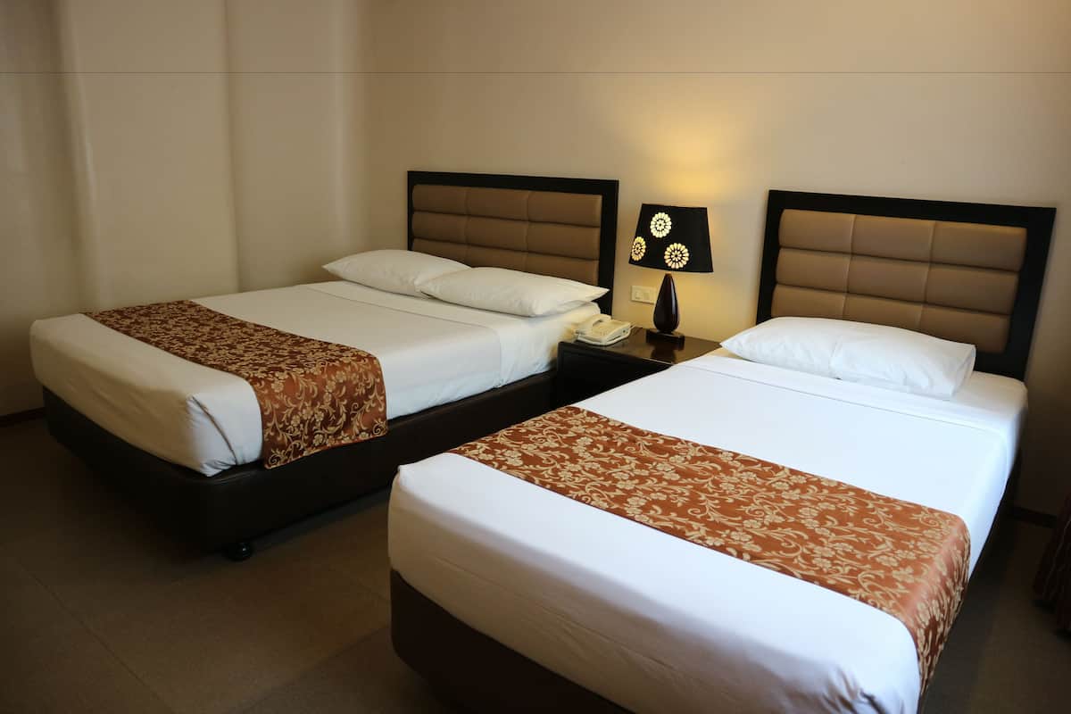 Two single beds with headboards, a bedside table with a lamp, and a telephone.