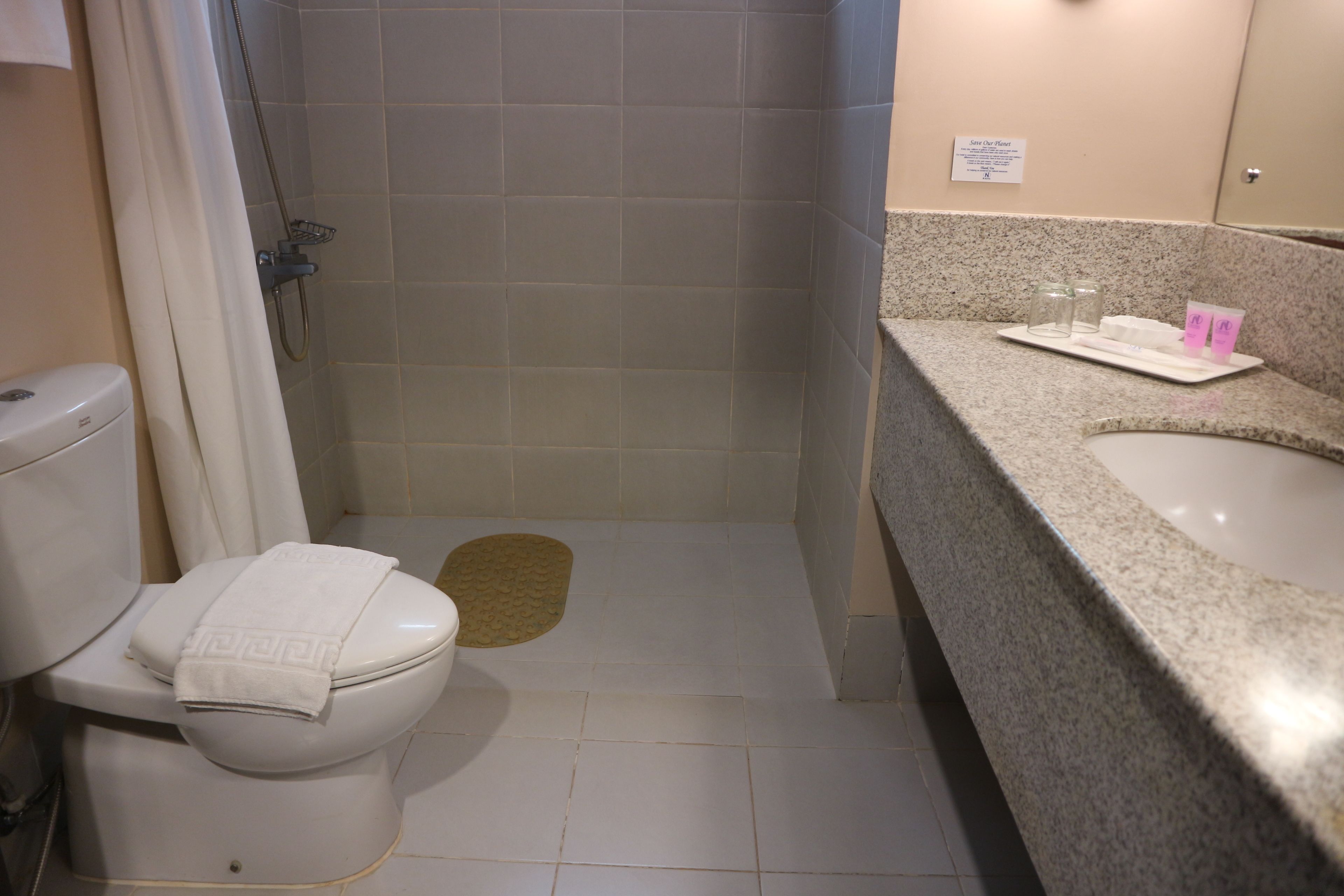 A bathroom with a toilet, shower, and sink.