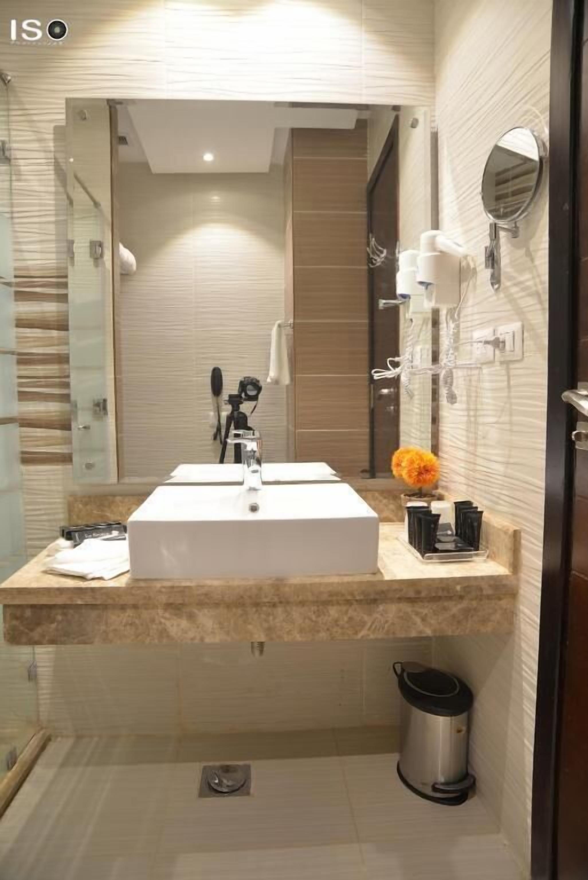 Une salle de bain moderne avec un grand lavabo, un miroir et une poubelle.