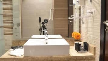 A modern bathroom with a large sink, a mirror, and a trash bin.