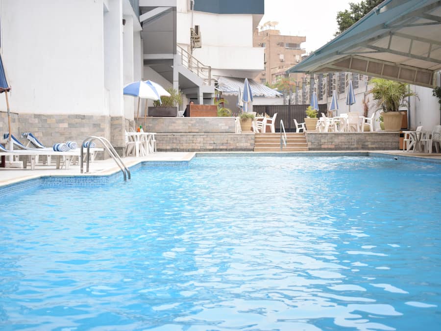 Una piscina al aire libre, sillones reclinables de piscina