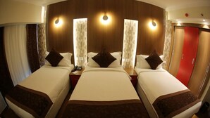 A hotel room with two beds, a wooden headboard, and a red door.