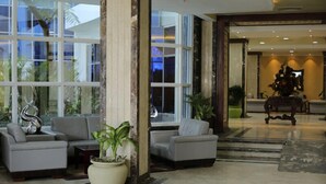 A modern lobby with a seating area, large windows, and a reception desk.