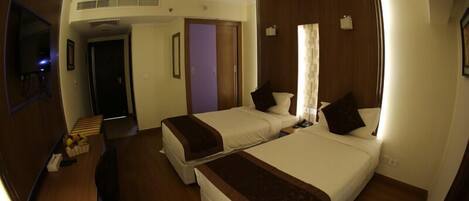 A hotel room with two beds, a desk, a chair, and a television.