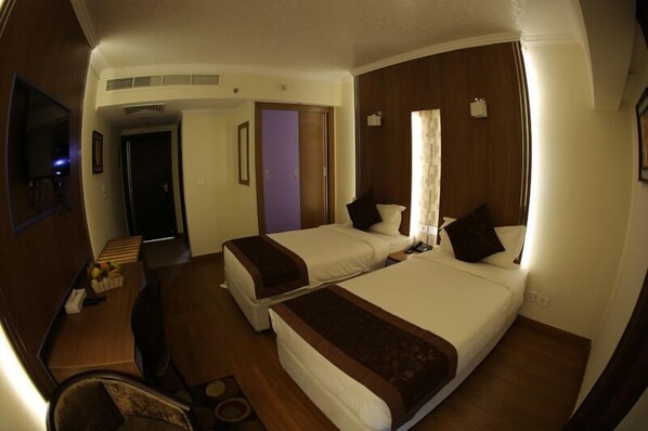 A hotel room with two beds, a desk, a chair, and a television. - Tolip Inn Maadi (Cairo)