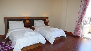 A hotel room with two beds, wooden headboards, bedside lamps, and a purple rug. - Gentle Hotel (Addis Ababa)
