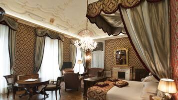 Un dormitorio lujoso con una cama grande, una araña y cortinas ornamentadas.