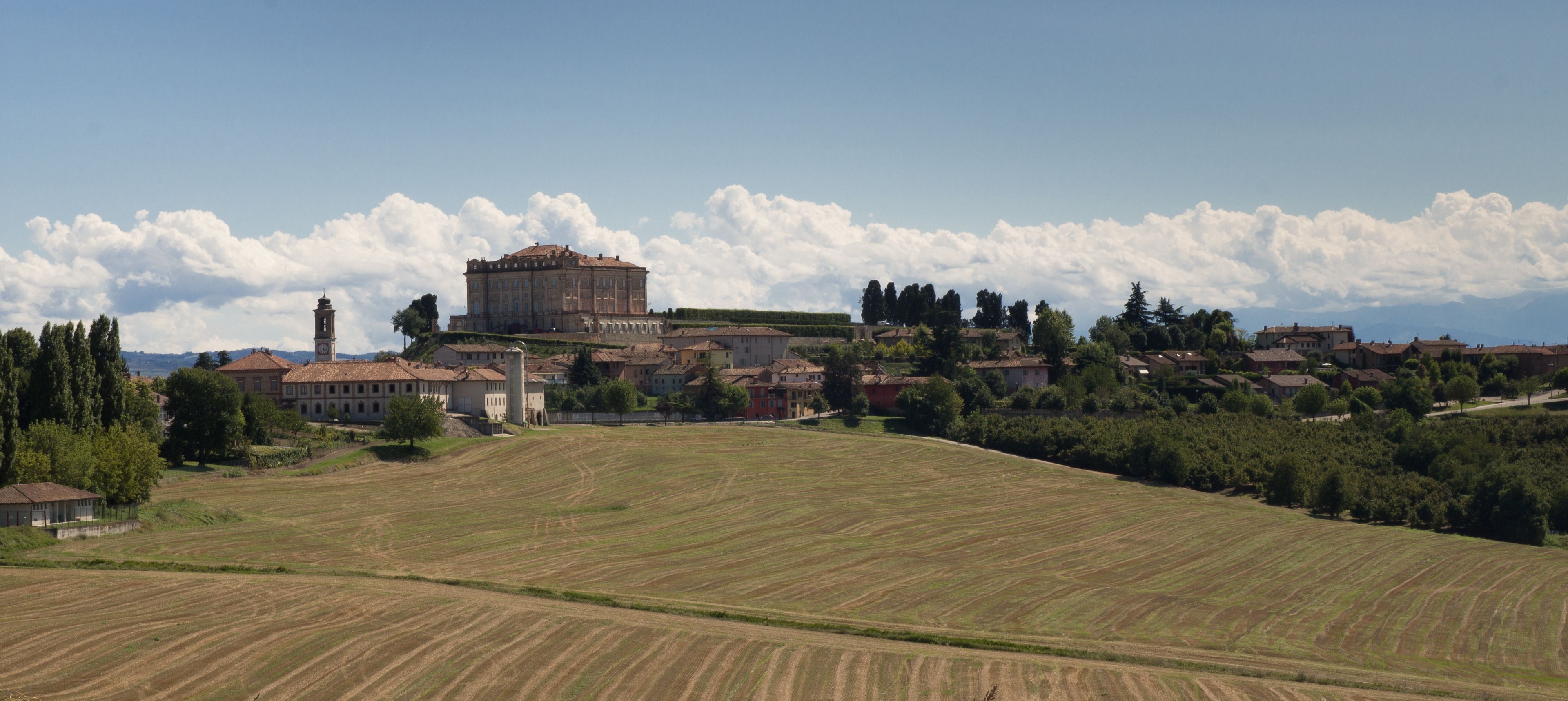 A historic town with a prominent building with a clock tower, surrounded by rolling hills and fields.