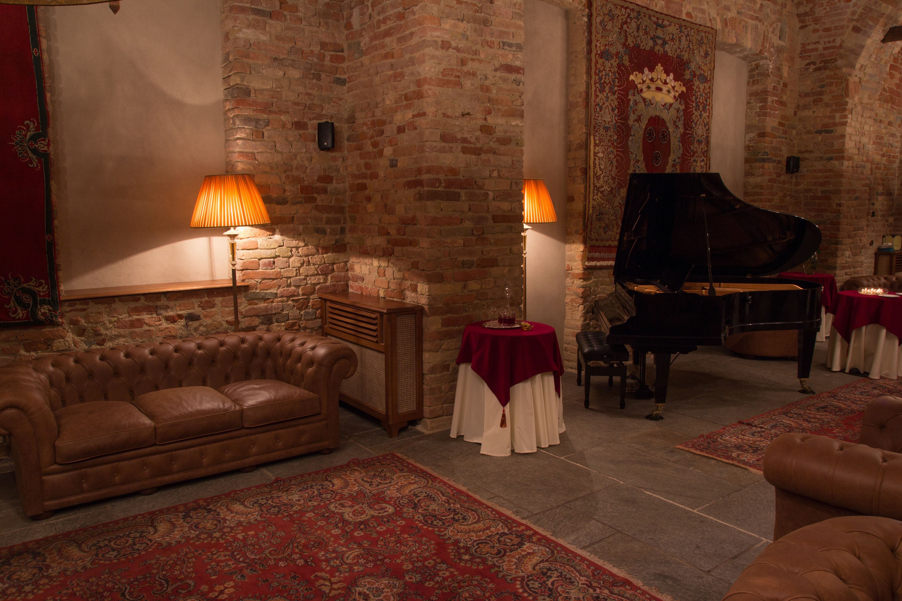 A cozy room with a leather sofa, a grand piano, and a red patterned rug.