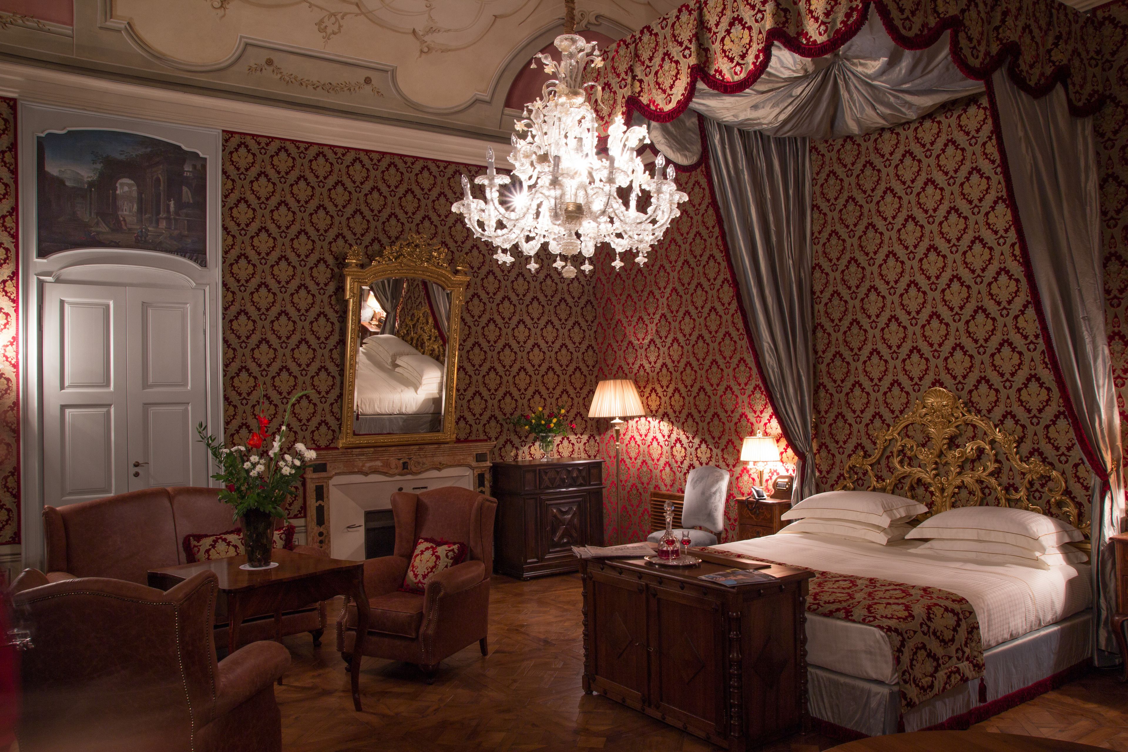 A luxurious bedroom with a large bed, ornate chandelier, and classic decor.