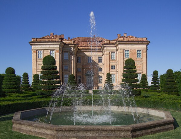 A large, historic building with a central fountain, surrounded by well-manicured hedges and a formal garden layout. - Castello di Guarene (Guarene)