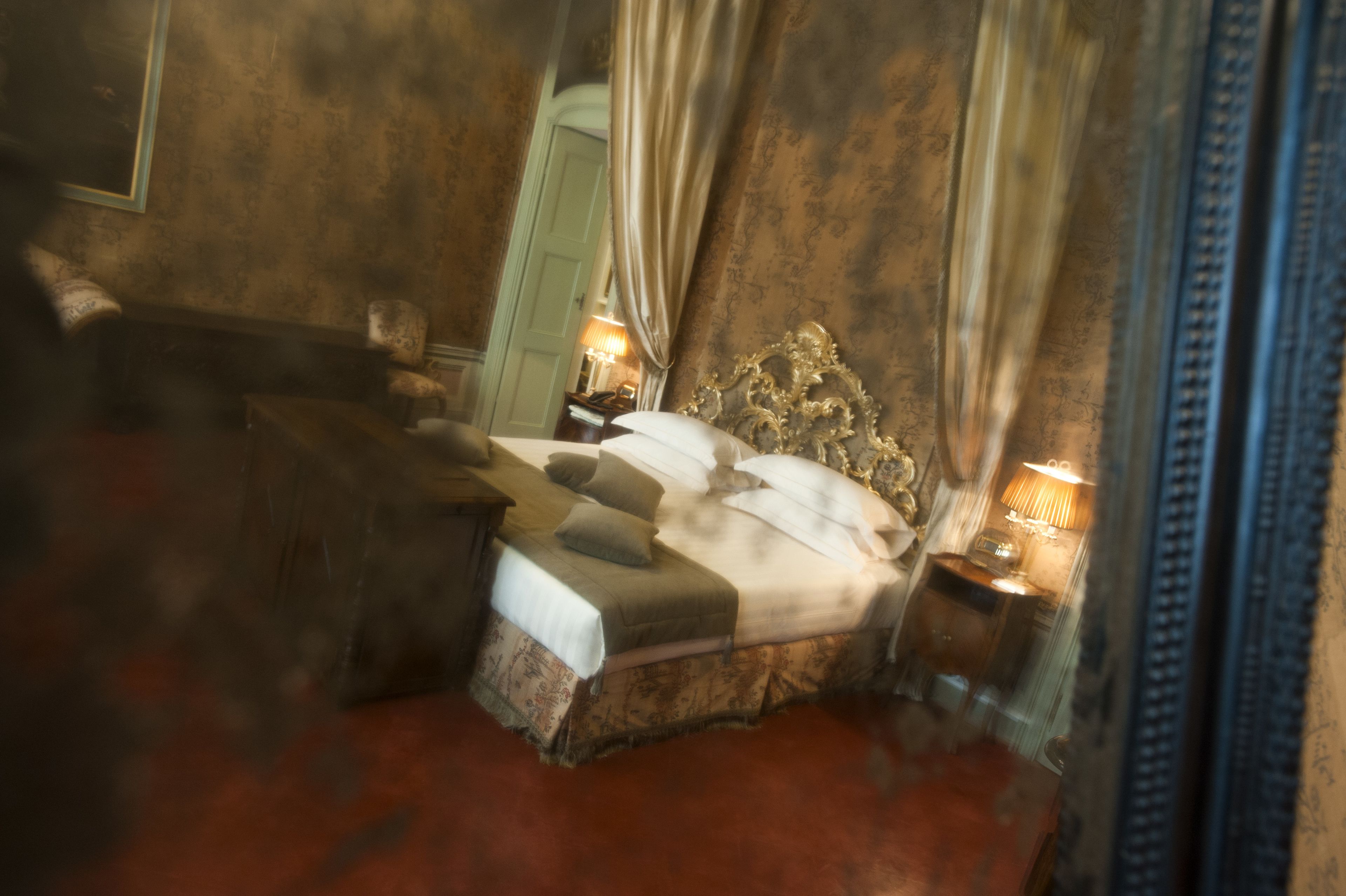 Une chambre à coucher avec un grand lit, une table de chevet avec une lampe et une chaise.