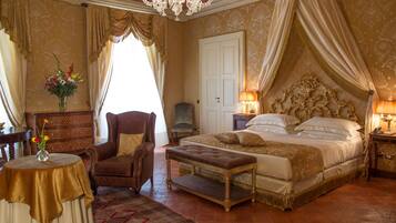 Un'elegante camera da letto con un ampio letto, una zona relax con una poltrona, un tavolino e un vaso decorativo.