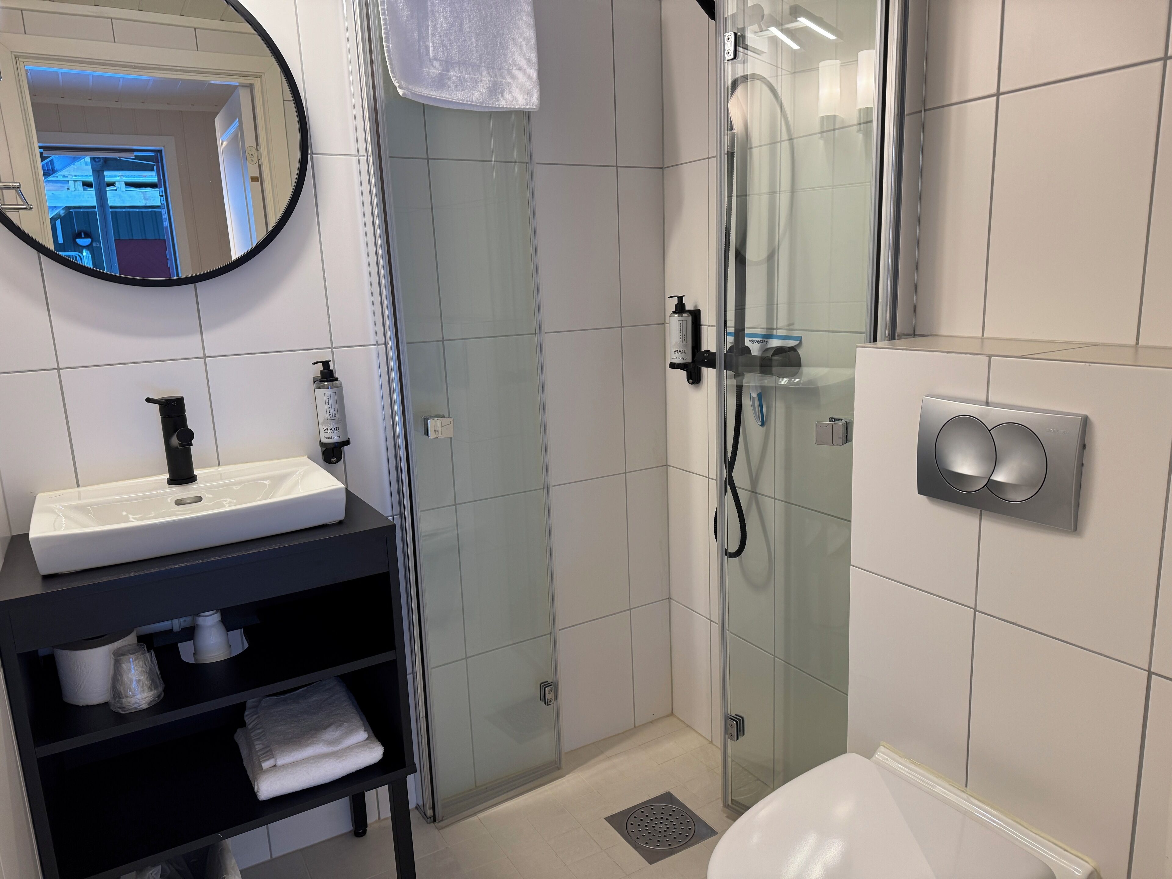 A modern bathroom with a glass-enclosed shower, a white sink with a black faucet, and a towel rack.