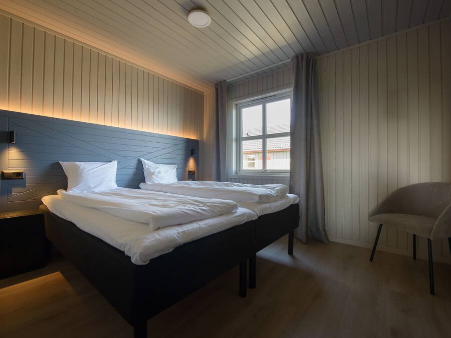 Un dormitorio moderno con una cama grande, mesitas de noche y una ventana con cortinas.