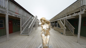 Une terrasse en bois ornée d’une statue représentant une femme en robe.