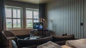 Une chambre d’hôtel avec un lit, un canapé, une télévision et une table avec deux verres.