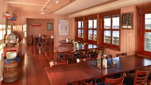 Un intérieur en bois avec plusieurs tables et chaises, une grande fenêtre offrant une belle vue et des éléments de décoration sur le thème de la marine.