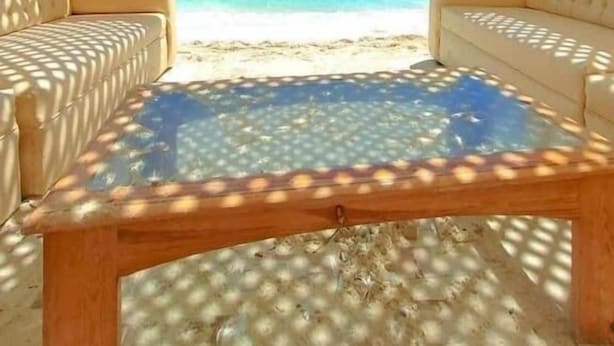 Een kamer met uitzicht op een strand, voorzien van twee banken en een salontafel.