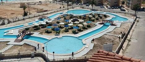 A resort with multiple swimming pools, a beach, and a view of the sea.