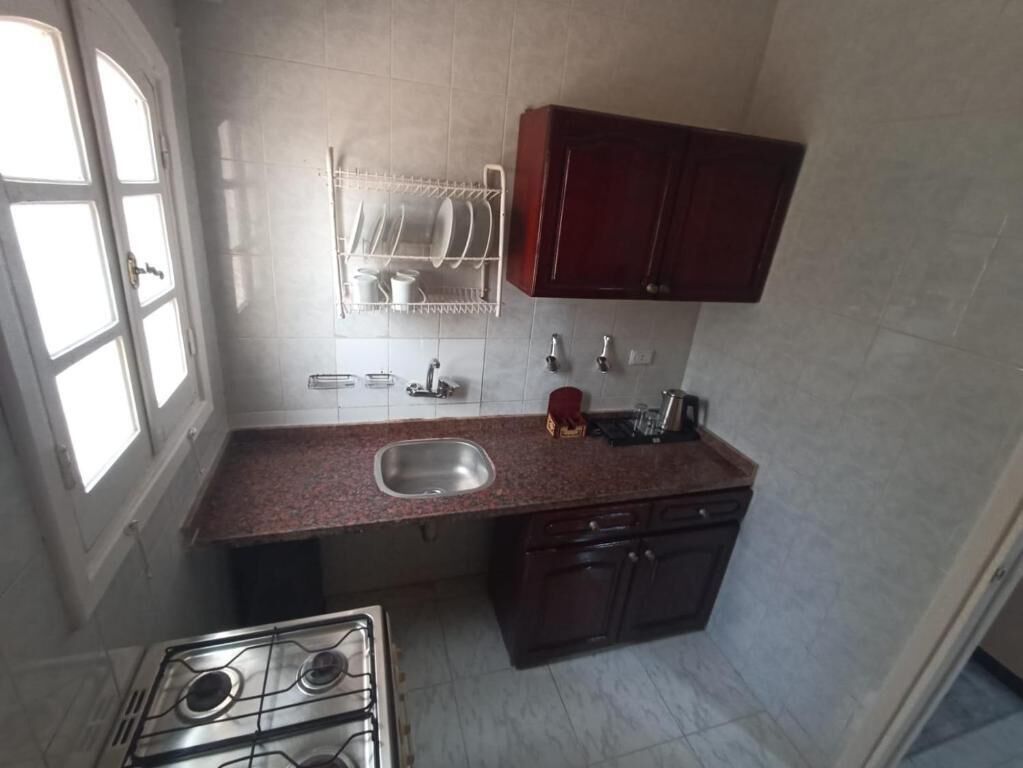 A compact kitchen with a gas stove, sink, and dark wooden cabinets.