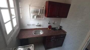 A compact kitchen with a gas stove, sink, and dark wooden cabinets.