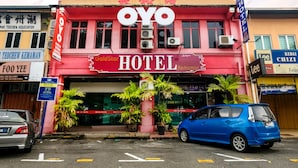 A hotel with a prominent 'OYO' sign, multiple air conditioning units, and potted plants in front. - OYO 850 Gold Star Hotel (Chukai)