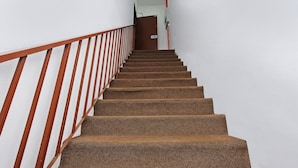 A carpeted staircase with wooden handrails leading to a door at the top. - OYO 850 Gold Star Hotel (Chukai)