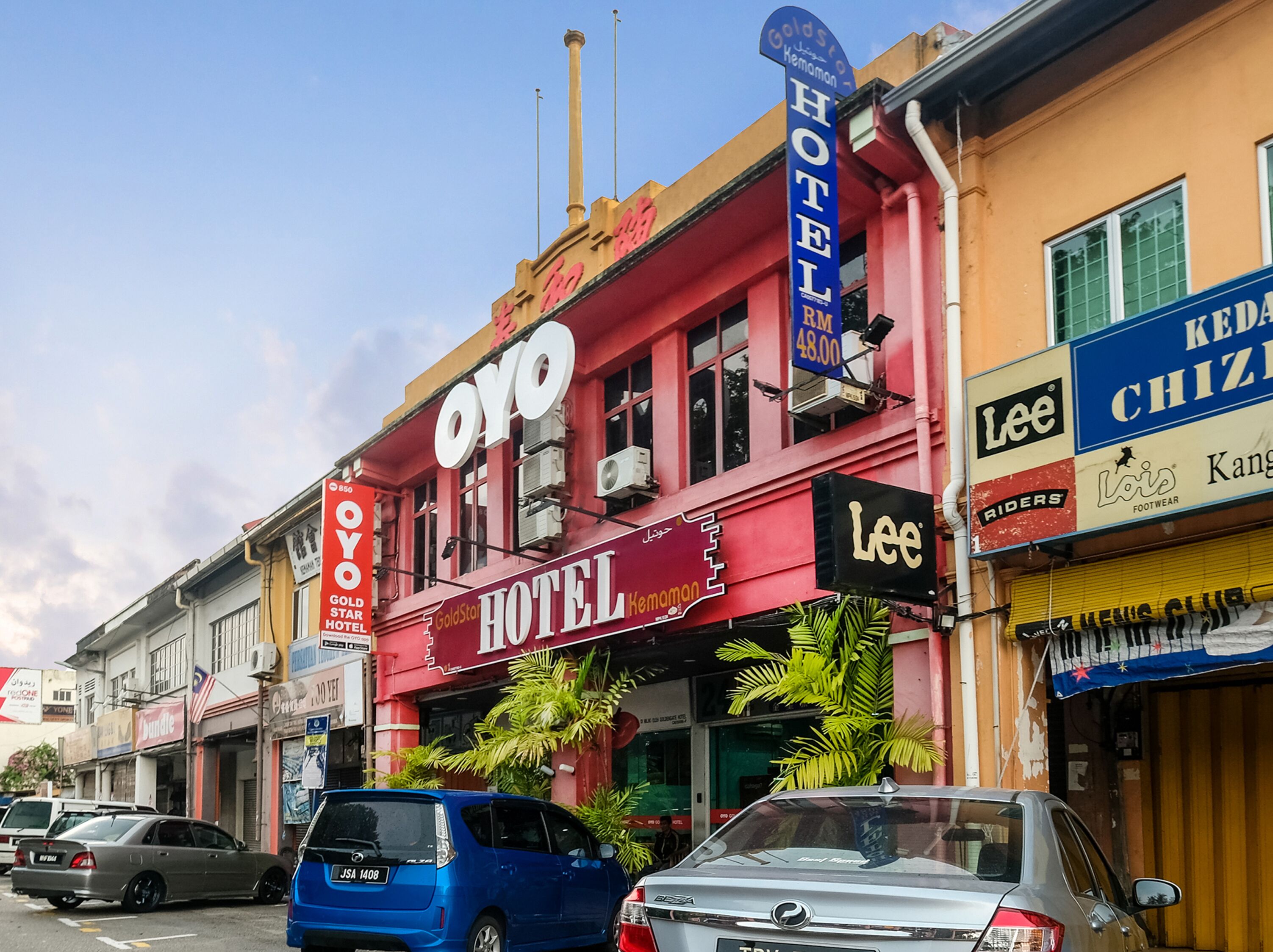 A hotel with a prominent 'OYO' sign, a 'Gold Star Hotel' sign, and a 'Lee' sign for footwear.