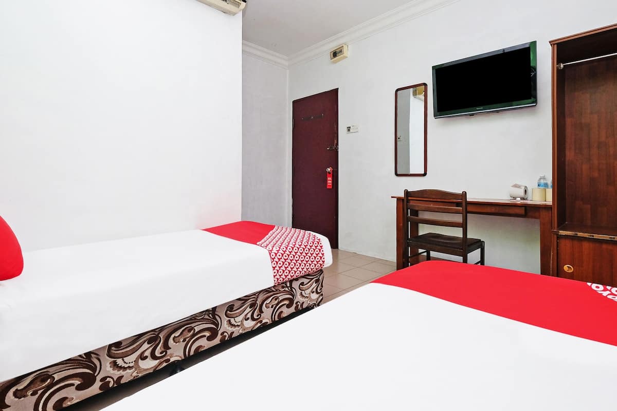 Habitación de hotel con dos camas, un escritorio, una silla, un televisor y un armario.