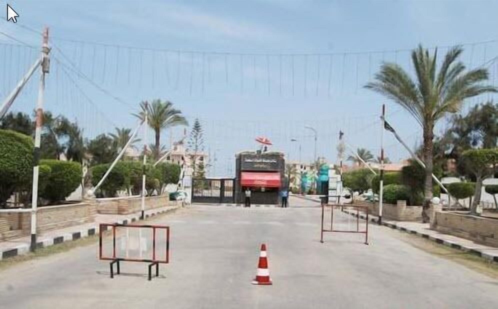 A road with a red and white traffic cone, a metal barrier, and a bus in the distance.